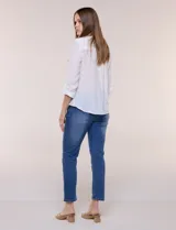 Blusa de calce relajado color salmón, confeccionada en tela liviana con textura sutil. Presenta escote en V con abotonadura frontal, bolsillo parche en el pecho, mangas largas regulables con presilla y ruedo con opción de anudar en el frente.