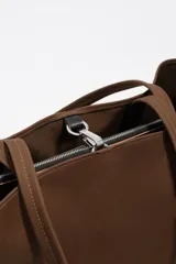 Bolso tipo shopper de Bimba y Lola, color marrón, confeccionado en gabardina con detalles en piel. Cuenta con doble asa de hombro y cierre principal con cremallera.