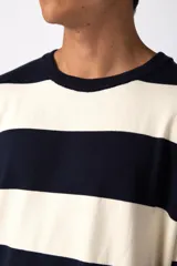 Remera de tejido de punto con diseño de rayas horizontales anchas en color bordó y crema, de corte holgado y cuello redondo.