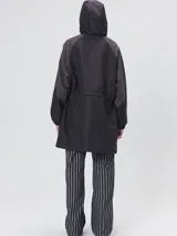 Campera tipo piloto con capucha, cierre frontal con botones y detalle de costuras en zigzag. Presenta cordones ajustables en la cintura y capucha, puños elásticos y logo bordado en el pecho.