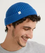 Gorro tipo fisherman de tejido acrílico con textura acanalada, diseño corto y etiqueta pequeña con logo en el frente.