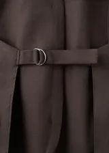 Chaleco marrón de lino y algodón, con diseño entallado, cuello halter, escote en pico, sin mangas, espalda abierta, bolsillos de ribete delanteros y cierre frontal de botones.