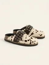 Zueco de cuero vacuno con estampado animal print tipo vaca, con hebilla decorativa metálica con ojales y suela de corcho con vira reforzada.