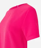 Blusa fucsia de manga corta con cuello redondo pespunteado, diseño sin estampa y efecto airflow con textura sutil. Cuenta con abertura trasera tipo gota y cierre con botón.