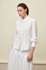 Camisa de manga larga color celeste, con cuello clásico y botonadura frontal. Presenta un calce relajado, con mangas amplias y puños anchos.