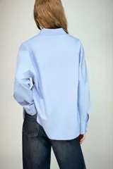 Camisa básica de corte clásico confeccionada en algodón, con cuello solapa, manga larga con puños abotonados, cierre frontal con botones y un bolsillo aplicado en el pecho.