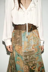 Falda midi plisada con estampado paisley en tonos verde agua, marrón y naranja. Presenta cintura elástica y un cinturón ancho marrón con hebilla dorada.