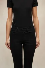 Jean de corte oxford en color negro, con tiro medio y ajuste en la cintura y caderas, ensanchándose desde la rodilla hacia el ruedo.