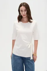Remera de manga corta color blanco con cuello redondo y detalle de lazo ajustable en el lateral.