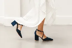 Zapato de taco alto azul oscuro, confeccionado en gamuza, con diseño de punta fina, escote en V y tiras cruzadas en diagonal con hebilla ajustable en el tobillo.