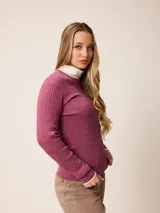 Sweater de punto con diseño de trenzas verticales, color negro, con cuello redondo, mangas largas y puños con detalle en contraste blanco. Presenta un pequeño logo bordado en el pecho.