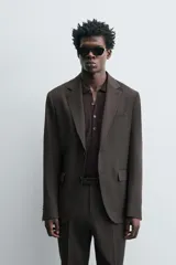 Blazer de corte regular confeccionada en tejido de lana. Presenta cuello con solapas de muesca, cierre frontal de un botón y manga larga con puños abotonados. Cuenta con bolsillos de vivo en el pecho, bolsillos con solapa en la cadera y aberturas en la parte posterior.