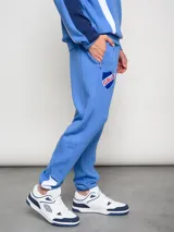 Pantalón deportivo azul claro con puños ajustados en los tobillos. Presenta el escudo del Club Nacional de Football bordado en la pierna izquierda y el logo de Umbro bordado en la derecha.