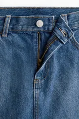 Minifalda de denim azul con diseño clásico de cinco bolsillos, trabillas para cinturón y cierre frontal con botón y cremallera.
