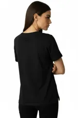 Remera de algodón negra con cuello redondo y mangas cortas. Presenta un estampado frontal con la frase 'WANTED AND WILD', gráficos de revólveres, estrellas y texto alusivo a un festival western.