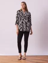 Blusa de gasa estampada con diseño geométrico multicolor, cuello a la base con escote en V y abertura frontal con botones. Presenta detalle de plisado en la parte delantera y mangas largas con sistema de ajuste mediante presilla y botón.