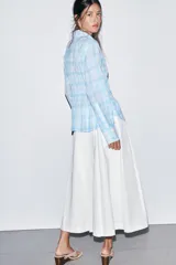 Falda midi de tiro alto en color blanco, con diseño acampanado y detalle de pliegues frontales. Cuenta con cierre lateral mediante cremallera oculta.