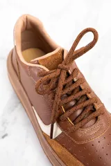 Zapatillas bajas de cuero color marrón con detalles en gamuza color tostado y talón en cuero dorado.