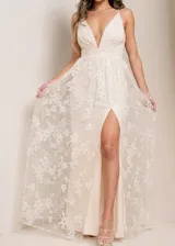 Vestido largo de fiesta con escote en V profundo y tirantes finos. Presenta una falda con tajo lateral, confeccionada en una base de tela lisa con una capa superior de encaje bordado con motivos florales y destellos brillantes.