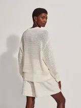 Sweater de punto calado color crema, de corte holgado y cuello redondo.