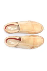 Zapato bajo de cuero color beige, con paneles elásticos laterales para un calce fácil y suela de goma dentada con logo grabado en el talón.