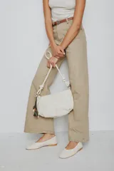 Cartera bandolera de cuero marrón con forma relajada, diseño de costuras curvas y detalles de nudos hechos a mano en las asas.
