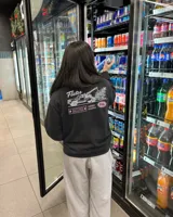 Buzo negro de cuello redondo y manga larga, de corte regular fit. En la espalda presenta un estampado gráfico en color blanco y rosa con la leyenda "Fletes" y el dibujo de una grúa transportando una planta.