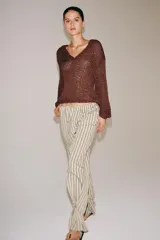 Pantalón de tiro medio con diseño de rayas verticales, confeccionado en mezcla de viscosa. Presenta cintura elástica ajustable con cordones, bolsillos laterales ocultos y pierna recta con bajo ajustable mediante botón.