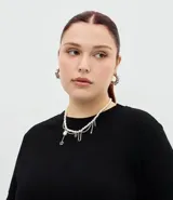 Blusa de manga corta con escote redondo, confeccionada en algodón. Presenta un diseño alargado con un detalle de encaje irregular aplicado en el ruedo, aportando un acabado asimétrico y delicado.
