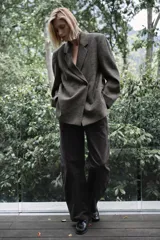 Blazer oversize de Zara confeccionado en hilatura con lana, con diseño de cuadros en tonos grises y líneas finas rojizas. Presenta cuello con solapa de muesca, cierre frontal cruzado con un botón, bolsillos de vivo en el delantero y forro interior.