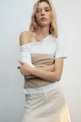 Top de escote asimétrico y manga corta, color blanco con fajín superpuesto a contraste en tono beige y detalles de frunces laterales.