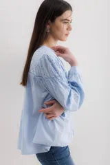 Camisa color crema de algodón con bordado calado, escote en V y mangas largas abullonadas.