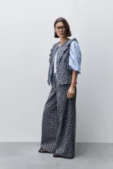 Pantalón de tiro alto con silueta amplia y piernas rectas, confeccionado en algodón con estampado floral. Cuenta con cierre frontal de botón y cremallera, y bolsillos laterales funcionales.