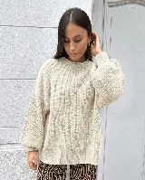 Sweater de punto color beige, con cuello redondo y mangas largas abullonadas con puños ajustados.