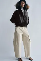 Chaqueta bomber de efecto piel en color marrón oscuro, con cuello solapa, cierre frontal con cremallera y botones, bolsillos delanteros, trabillas en los hombros y puños y bajo elásticos.