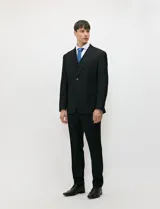 Traje de tres piezas color negro, compuesto por saco de dos botones, chaleco entallado y pantalón de corte slim, confeccionado en tejido de fantasía con spandex.