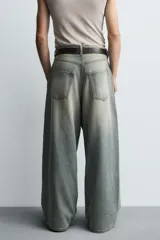 Jeans de denim de algodón, color azul oscuro con efecto lavado. Presentan un corte muy holgado (baggy fit) en toda la pierna y tiro medio. Tienen cinco bolsillos y cierre frontal con cremallera y botón.