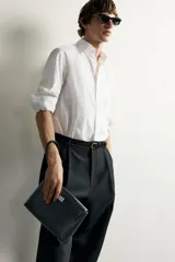Bolso de mano tipo sobre negro, de acabado liso, con solapa y cierre de pieza metálica giratoria. Incluye asa de mano.