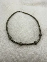 Collar corto de cuentas facetadas color dorado con tres dijes cúbicos de pirita.