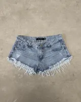 Short de jean tiro medio color celeste con efecto lavado, roturas sutiles y terminación desmechada con flecos en el ruedo.