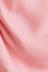 Top sin mangas de satén color rosado, con escote bote, diseño drapeado y tiras decorativas en un hombro.
