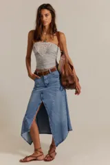 Falda larga de denim, de tiro medio y línea A, con abertura frontal, paneles con costuras y ruedo deshilachado en punta.