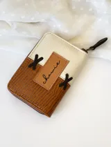 Billetera pequeña de cuero color camel y crudo, con cierre metálico y detalle de cruces bordadas en hilo negro.