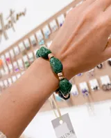 Pulsera elástica compuesta por piedras naturales de color verde oscuro con acabado irregular y separadores metálicos en tono dorado.