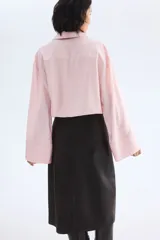 Camisa oversize de manga larga en mezcla de viscosa, color rosado claro. Cuenta con cuello camisero clásico, cierre frontal con botonadura oculta y canesú en la espalda. Presenta hombros caídos, puños anchos y bajo recto con aberturas laterales.