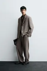 Pantalón de traje de corte slim fit, color marrón con textura sutil. Cuenta con cierre frontal de cremallera y botón, bolsillos laterales y bolsillos traseros de doble vivo con botón.