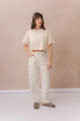 Jean de tiro alto confeccionado en denim color crudo, con estampa de estrellas en tono camel. Presenta calce relajado, pierna recta levemente amplia, costuras verticales delanteras, cinco bolsillos, pasacintos y detalle metálico en la parte posterior.