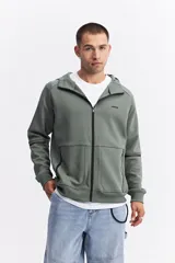 Campera con capucha y cierre frontal, color beige, con detalles de costuras y cierres en negro. Presenta mangas largas con puños acanalados y logo pequeño en el pecho.