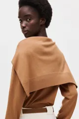 Sweater de punto fino color marrón, de cuello redondo con ribetes en canalé. Presenta un diseño que incluye un fular a juego anudado alrededor de los hombros, simulando el efecto de otro jersey sobrepuesto.