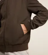 Campera bomber negra para hombre, confeccionada en poliéster con cierre frontal de cremallera, cuello, puños y dobladillo elásticos acanalados, y bolsillos laterales.